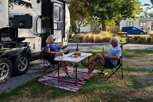 Photo of a couple relaxing outside a caravan.